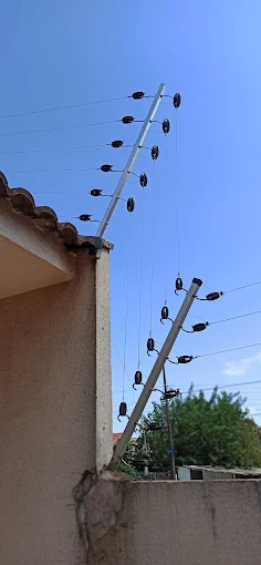Cerca elétrica com hastes e fios instalada sobre o muro dos fundos de uma casa