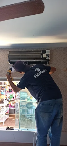 Técnico fazendo a limpeza da evaporadora do ar-condicionado dentro de uma loja