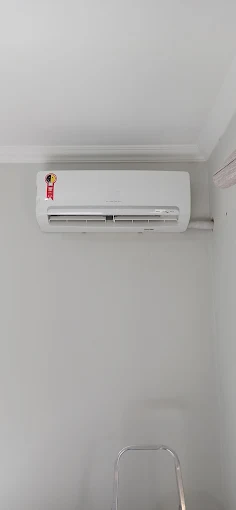 Ar-condicionado split instalado na parede branca de um quarto