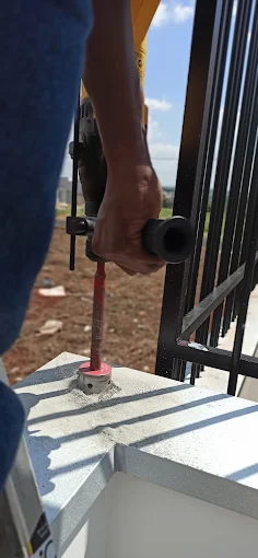 Furadeira abrindo o furo na base de concreto para chumbar o motor do portão