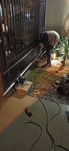 Técnico instalando o motor de um portão deslizante na entrada de uma residência