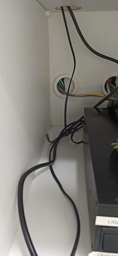 Cabos de rede passando pela parede até o equipamento instalado no canto da sala