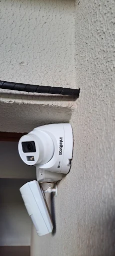 Câmera de segurança colorida e sensor infravermelho instalados na parede externa de uma residência